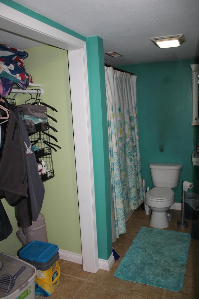 full bathroom with tile patterned floors, curtained shower, toilet, and baseboards