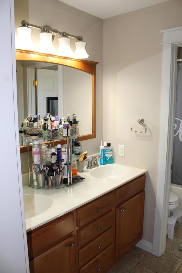 bathroom featuring a sink, toilet, double vanity, and tile patterned floors