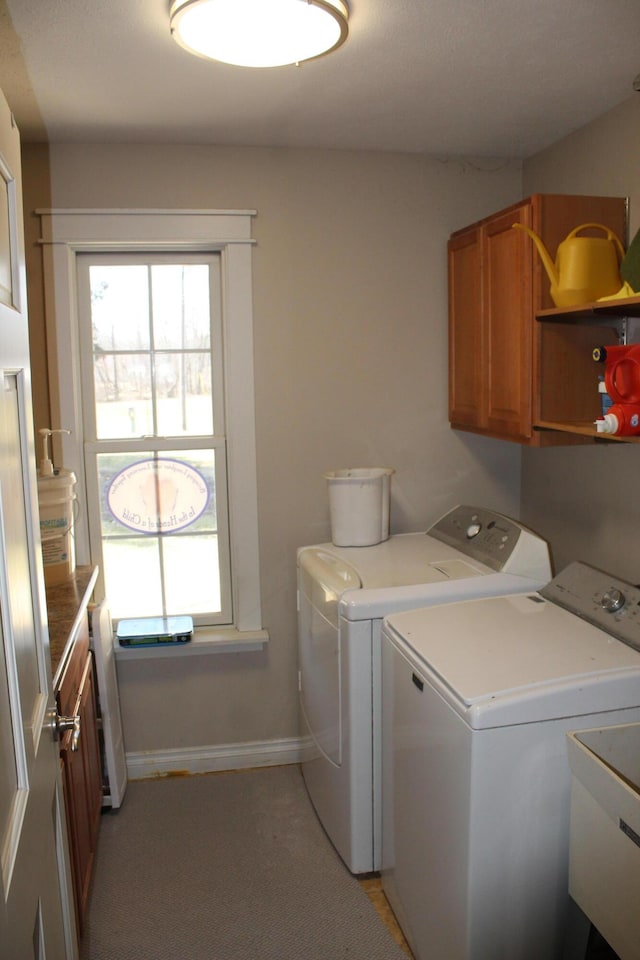 clothes washing area featuring washer and dryer, cabinet space, baseboards, and a sink