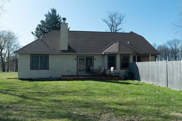 rear view of house featuring a yard, roof with shingles, fence, and a chimney