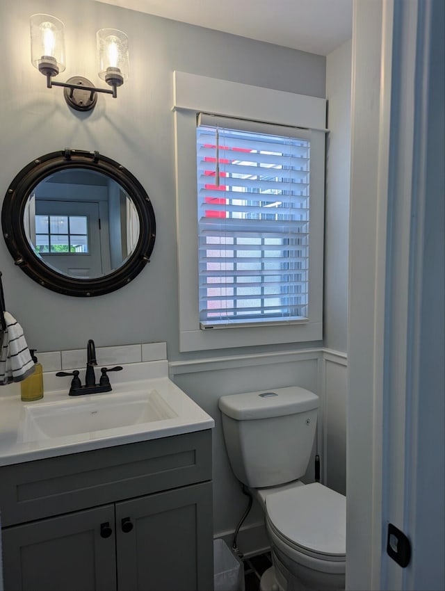 bathroom featuring vanity, a decorative wall, and toilet