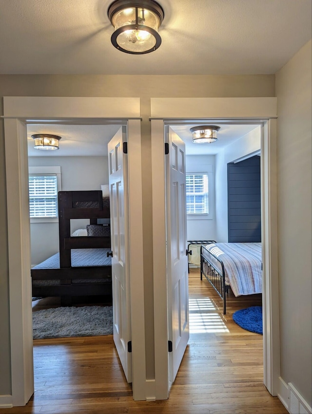 corridor with wood finished floors and visible vents