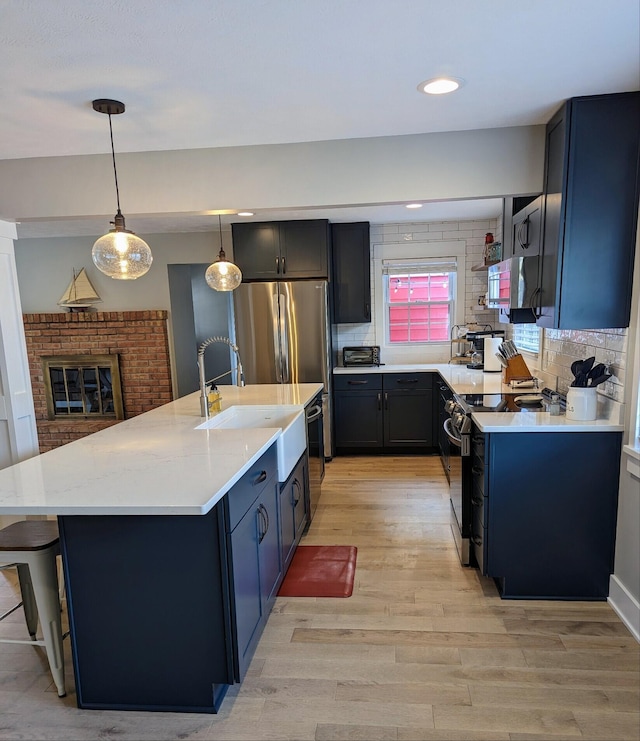 kitchen featuring a sink, stainless steel appliances, light wood-style floors, and backsplash