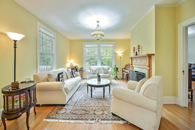 living area featuring baseboards, wood finished floors, a fireplace, and crown molding