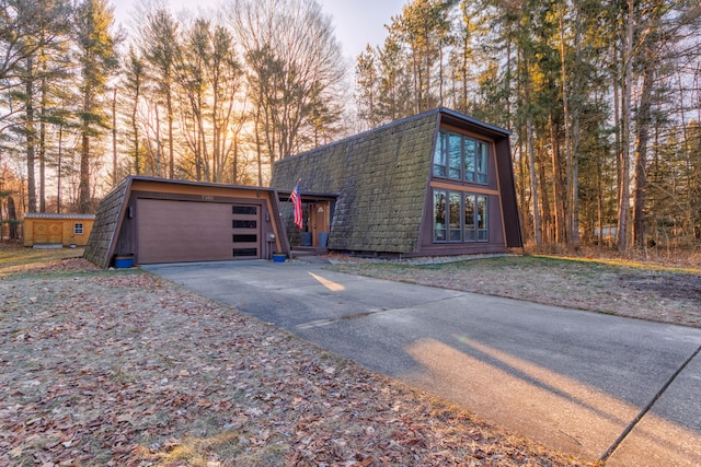 a-frame style home with aphalt driveway, an attached garage, and a shingled roof