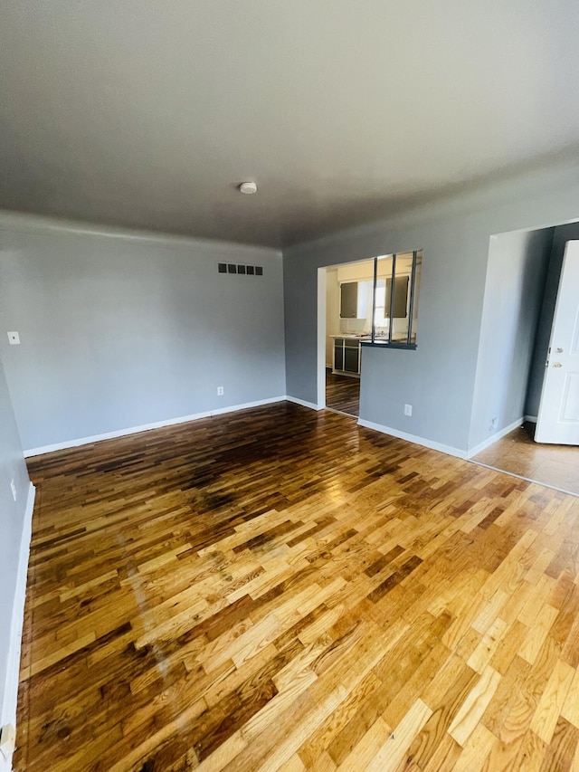 spare room featuring wood finished floors, baseboards, and visible vents