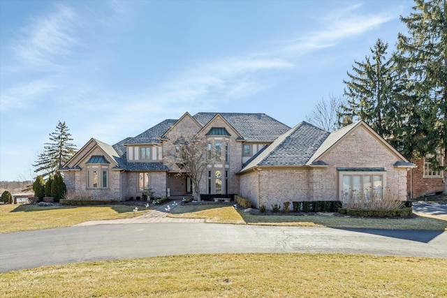 french country inspired facade with brick siding and a front yard