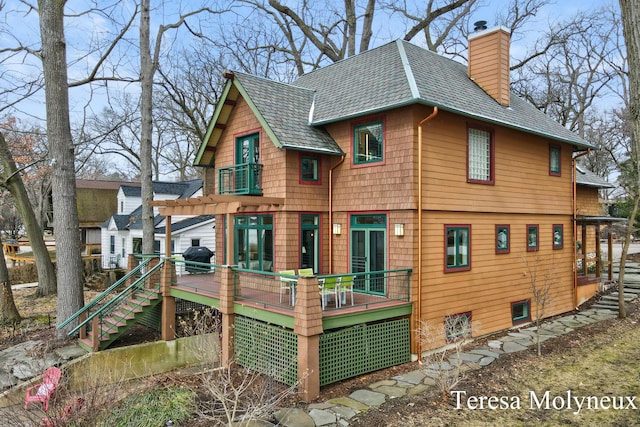 exterior space featuring a balcony, a shingled roof, stairs, a chimney, and a deck