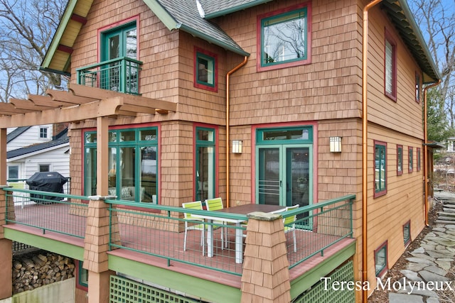 back of house with a balcony, a pergola, a deck, and a shingled roof