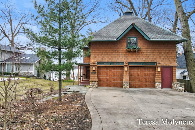 view of front of property featuring a garage, stone siding, driveway, and a shingled roof