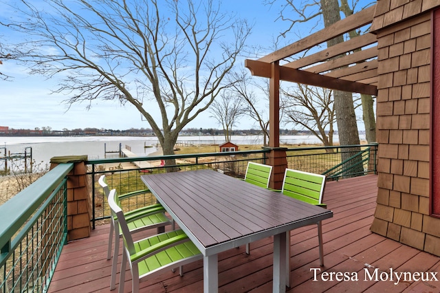 deck featuring a pergola, outdoor dining area, and a water view