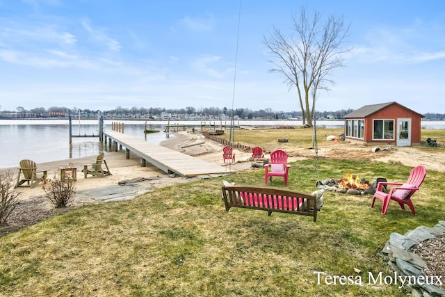 view of yard with an outbuilding, an outdoor fire pit, a dock, and a water view