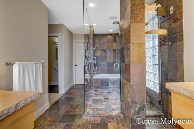 bathroom featuring vanity, baseboards, a stall shower, and stone tile flooring