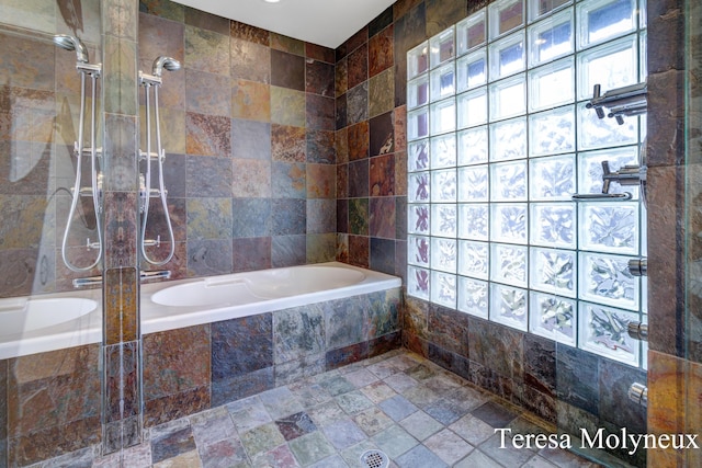 full bath with a relaxing tiled tub, tiled shower, and stone finish flooring