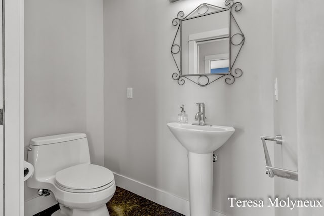 bathroom featuring toilet and baseboards