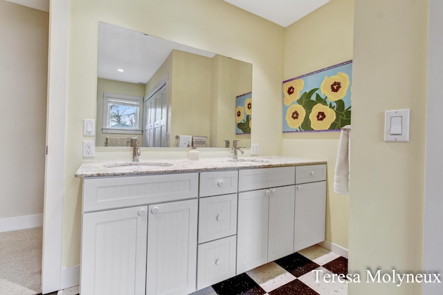 full bathroom with double vanity, baseboards, and a sink