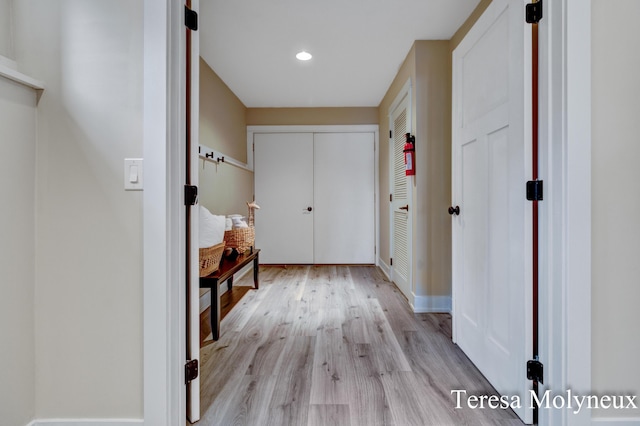 hall featuring light wood-style flooring, recessed lighting, and baseboards