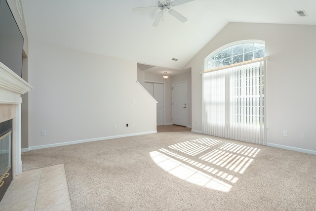 unfurnished living room with visible vents, light carpet, high vaulted ceiling, and a tile fireplace