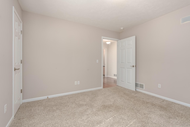 carpeted empty room with visible vents and baseboards