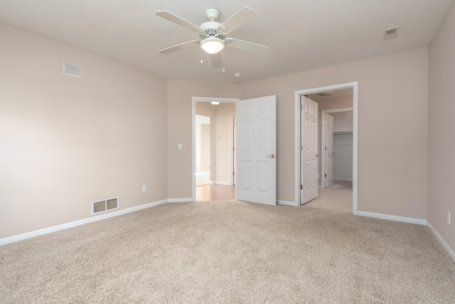 unfurnished bedroom with a spacious closet, baseboards, visible vents, and light carpet