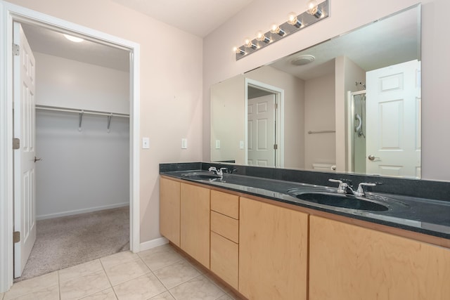 bathroom featuring double vanity, toilet, a stall shower, and a sink