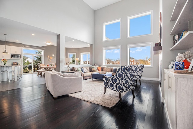 living room featuring baseboards, recessed lighting, dark wood-style flooring, and a high ceiling