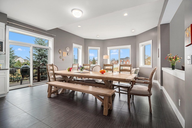 dining area with baseboards, recessed lighting, a wealth of natural light, and dark tile patterned flooring