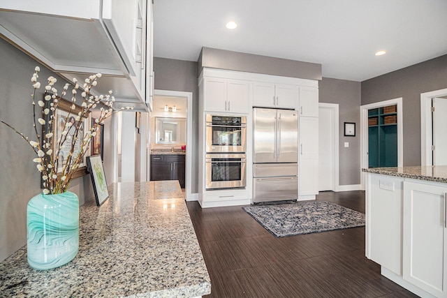 kitchen with light stone countertops, baseboards, recessed lighting, white cabinets, and stainless steel appliances