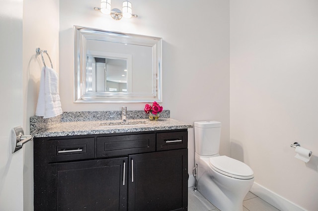bathroom featuring vanity, tile patterned flooring, baseboards, and toilet