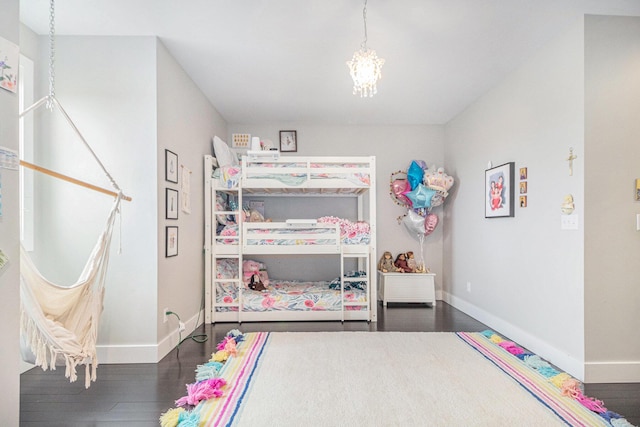 bedroom with baseboards, an inviting chandelier, and wood finished floors