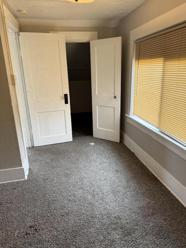 unfurnished bedroom with carpet flooring, baseboards, a closet, and a textured ceiling