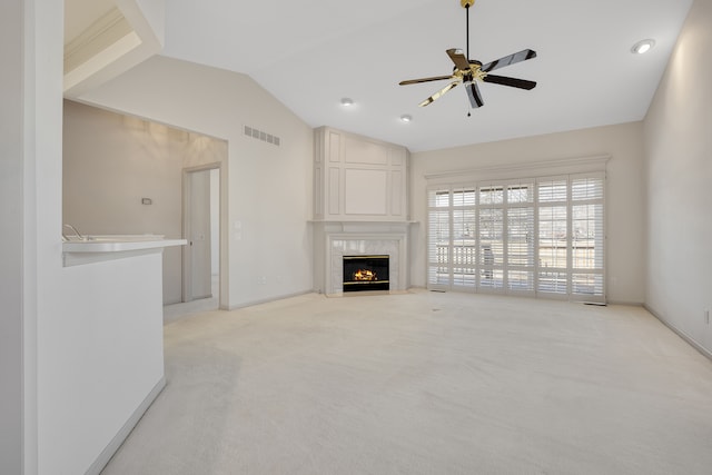 unfurnished living room with a ceiling fan, visible vents, a fireplace, vaulted ceiling, and light colored carpet