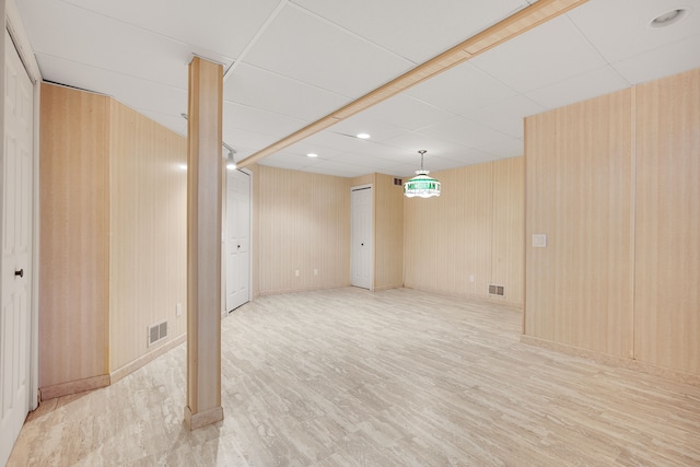 finished basement with visible vents, a paneled ceiling, and wood finished floors