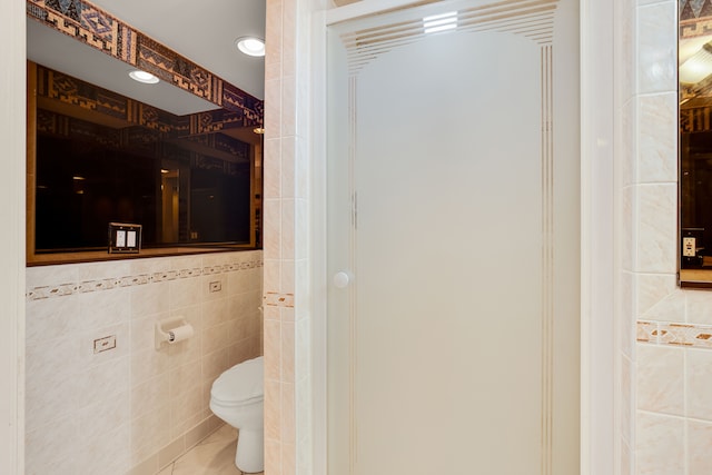 bathroom featuring toilet, tile walls, and tile patterned flooring