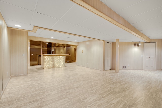 unfurnished living room featuring recessed lighting, a dry bar, a paneled ceiling, and wood finished floors