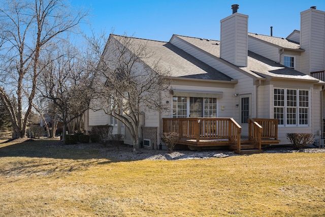 rear view of house featuring a chimney, a lawn, a wooden deck, and a shingled roof