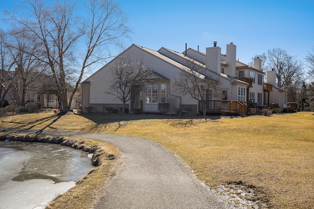 view of front of home featuring a chimney, a deck, and a front yard