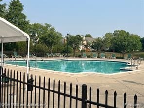 community pool with a patio area and fence