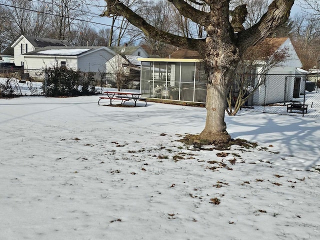 yard covered in snow featuring a sunroom and fence