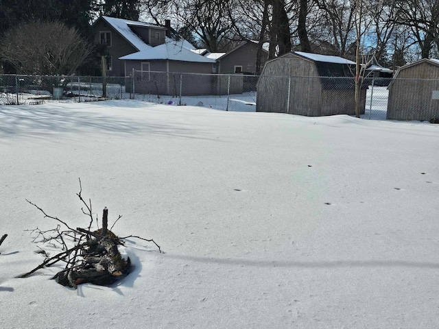 yard covered in snow with an outbuilding, a storage shed, and fence