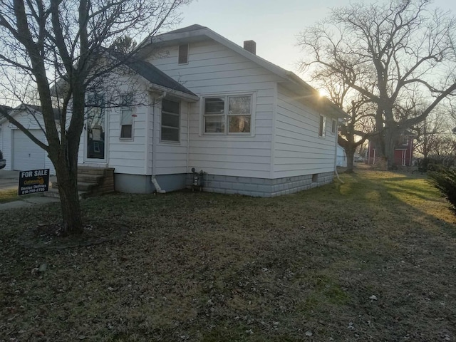 view of side of property featuring a lawn, entry steps, and a chimney