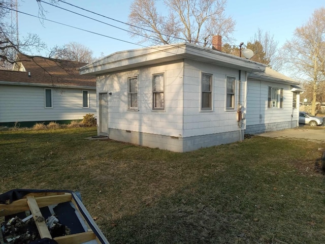 view of property exterior with crawl space, a lawn, and a chimney