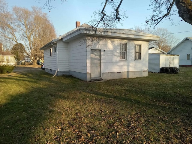 view of home's exterior featuring crawl space, a lawn, and a chimney