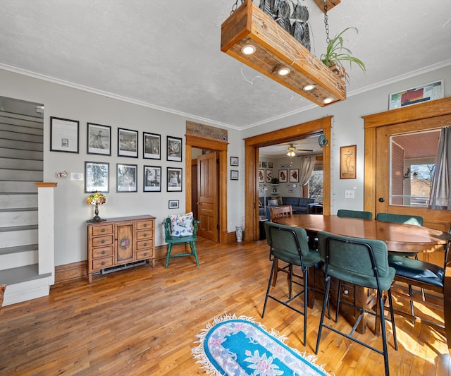 dining space featuring stairs, a textured ceiling, crown molding, and light wood finished floors