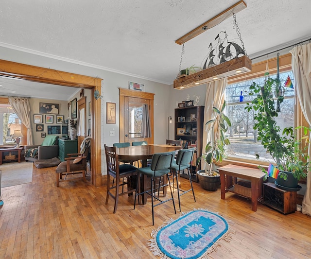 dining space with a textured ceiling, crown molding, and hardwood / wood-style flooring