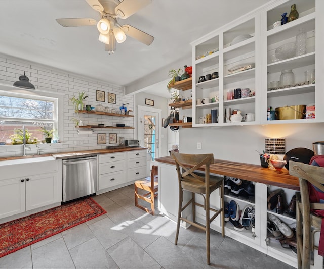 kitchen with light tile patterned floors, white cabinetry, open shelves, a sink, and dishwasher