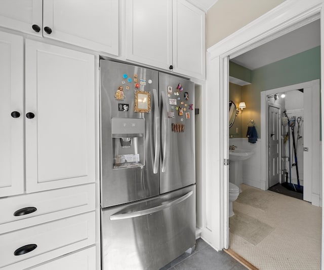 kitchen with light tile patterned flooring, stainless steel refrigerator with ice dispenser, and white cabinetry