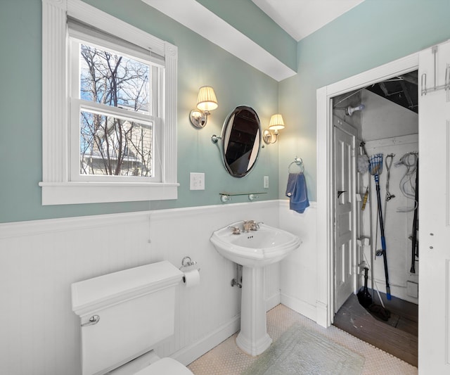 bathroom with toilet, a wainscoted wall, and a sink