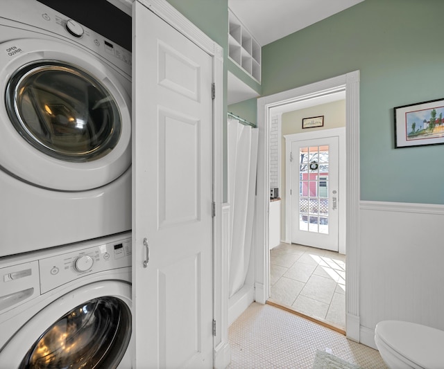 washroom featuring laundry area, wainscoting, and stacked washing maching and dryer