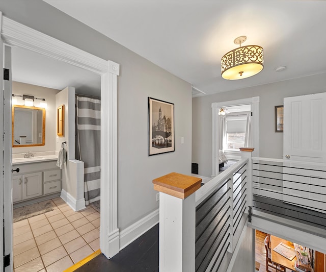 hall featuring a sink, baseboards, and tile patterned floors